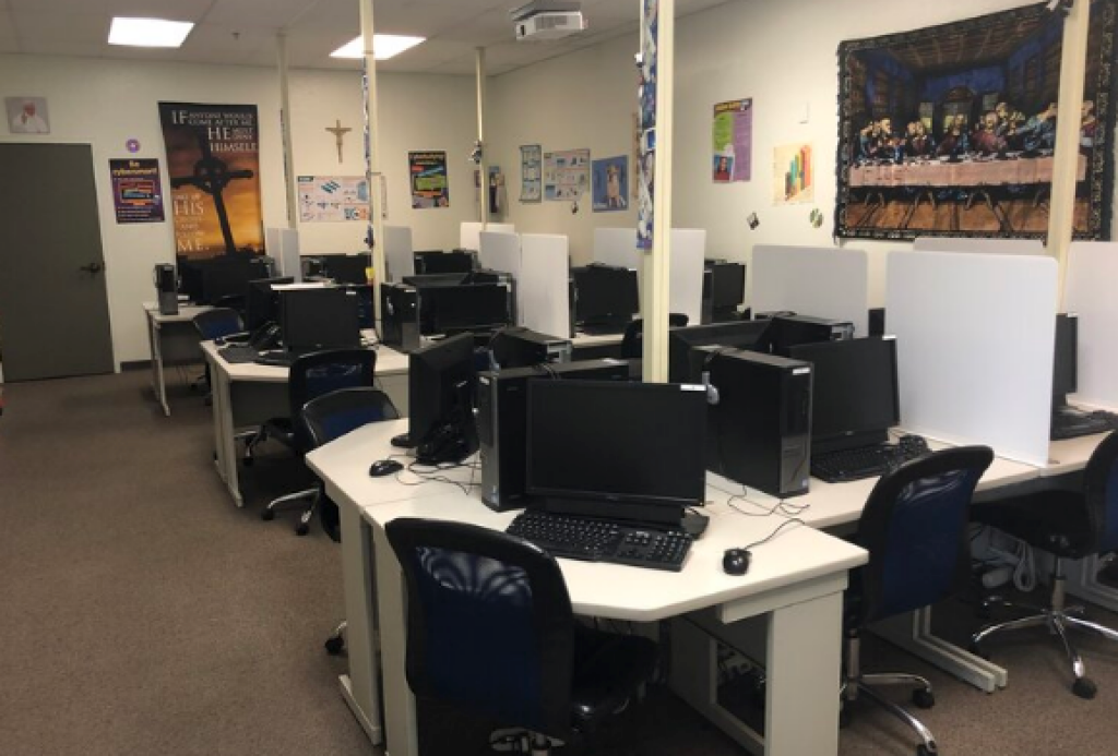 Computer lab with rows of desks, monitors, and chairs in a carpeted office space