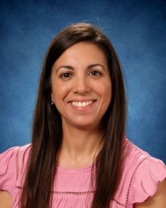 Smiling woman in a pink top against a blue studio backdrop