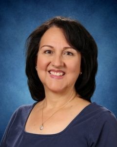Portrait of a smiling woman with dark hair against a blue studio background