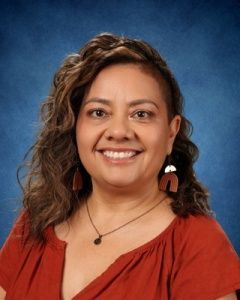 Smiling woman in a red blouse against a blue studio backdrop