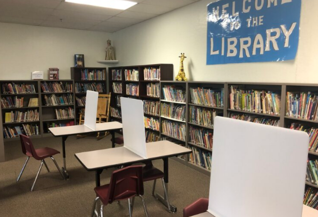 Library room with bookshelves, tables, chairs, and a blue “Welcome to the Library” sign on the wall