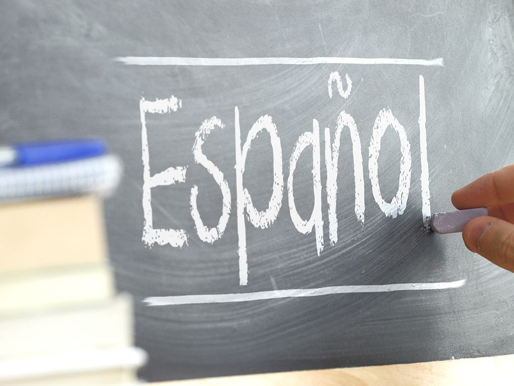 “Español” written on a chalkboard beside stacked books and chalk