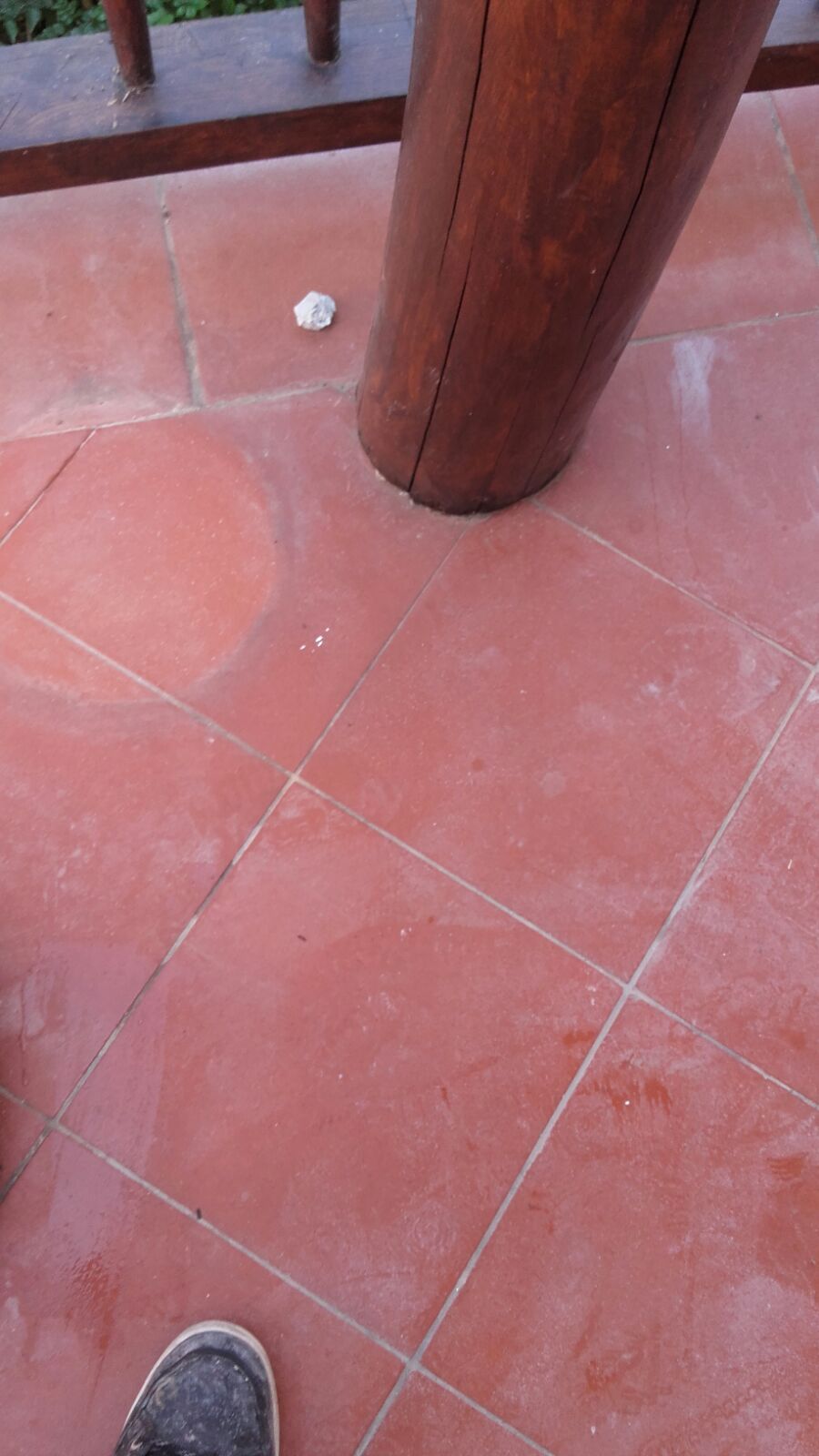 Pavimento in piastrelle rosse con un pilastro di legno e un piccolo oggetto.