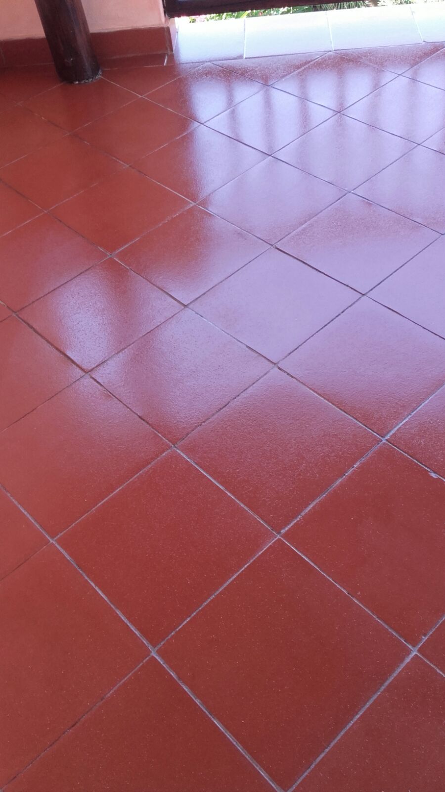 Pavimento esterno piastrellato di rosso, che riflette la luce.