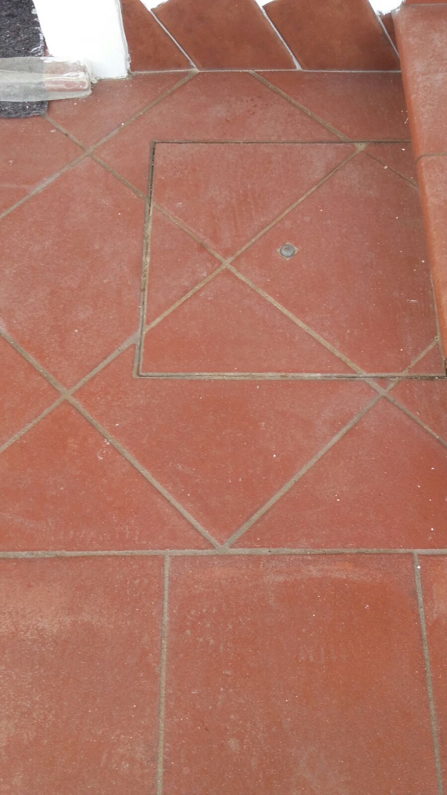 Pavimento in cotto con pannello di accesso quadrato.