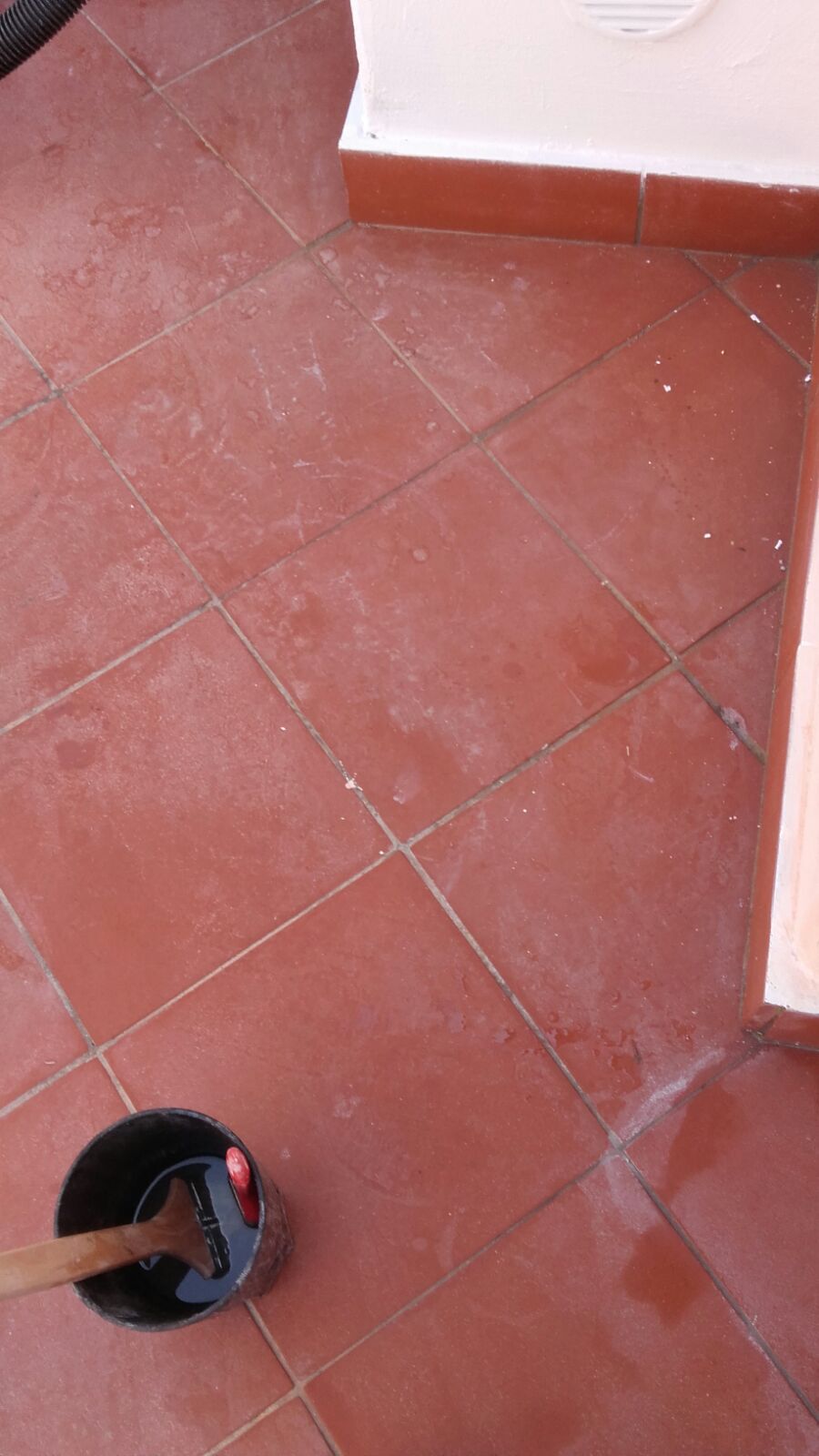Pavimento piastrellato marrone pulito con un secchio e una spazzola.
