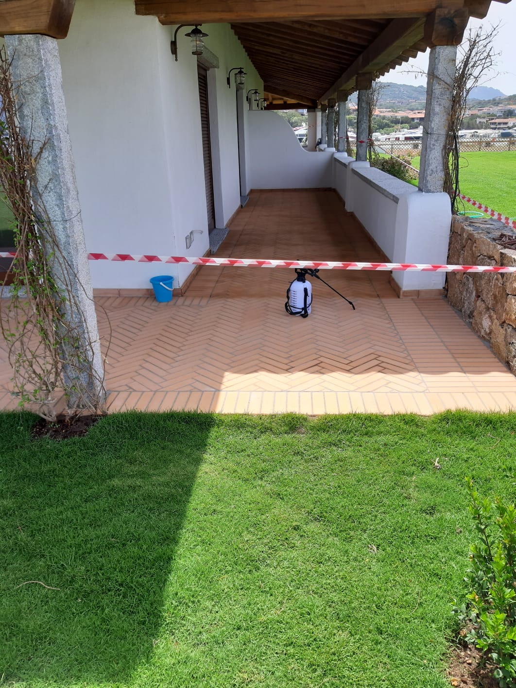 Un patio in mattoni con uno spruzzatore, nastro di segnalazione e un prato.