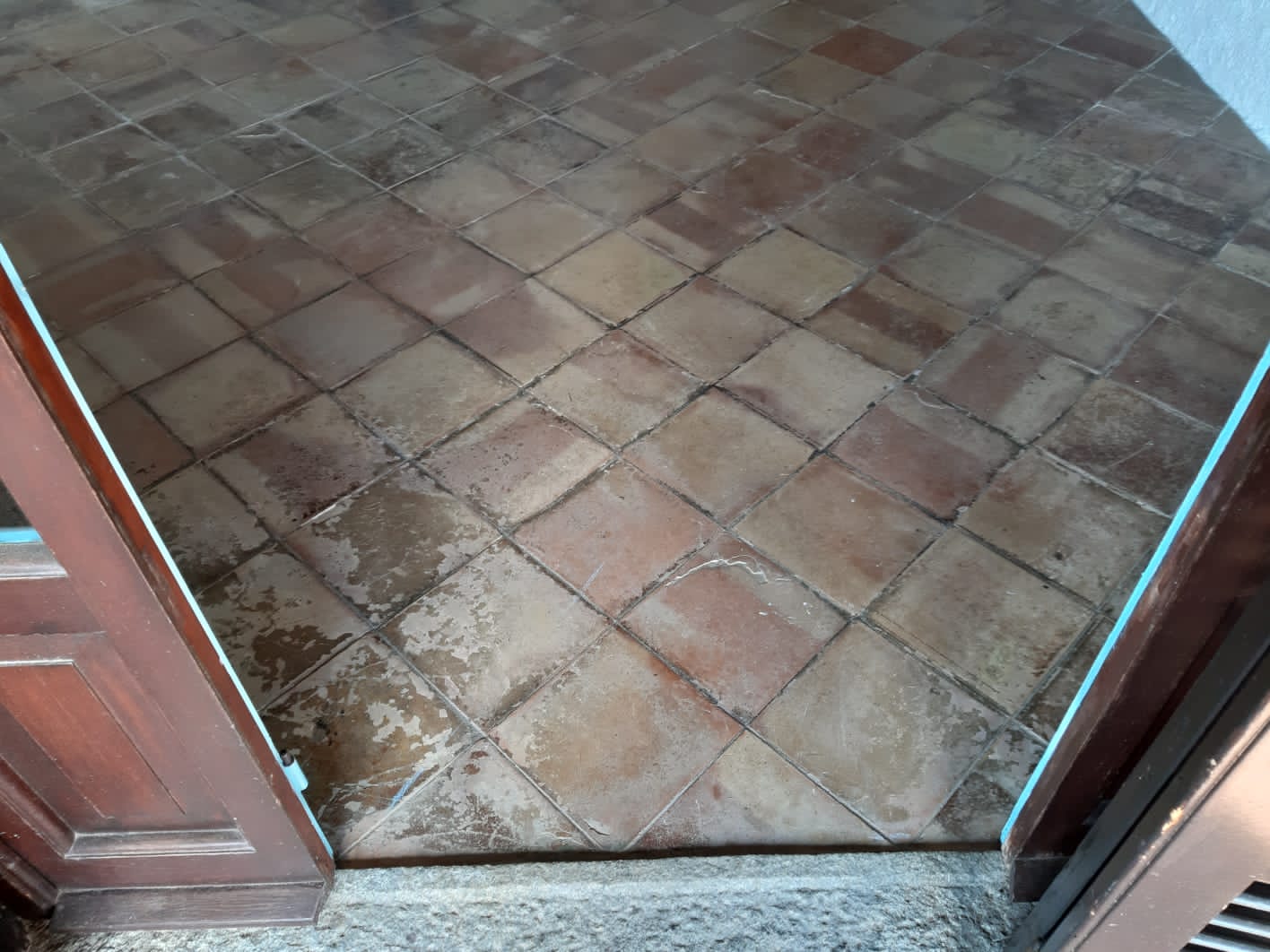 Pavimento in cotto visto dalla porta, piastrelle con motivo a rombi.