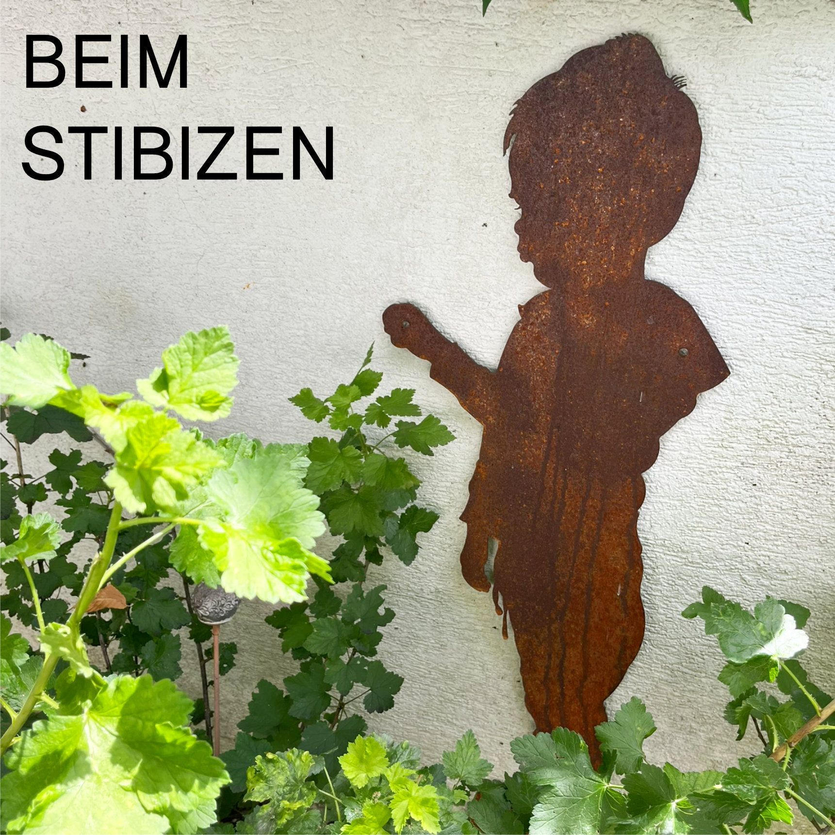 Die rostige Metallsilhouette eines Kindes, das nach Grün greift, hebt sich von einer weißen Wand ab.