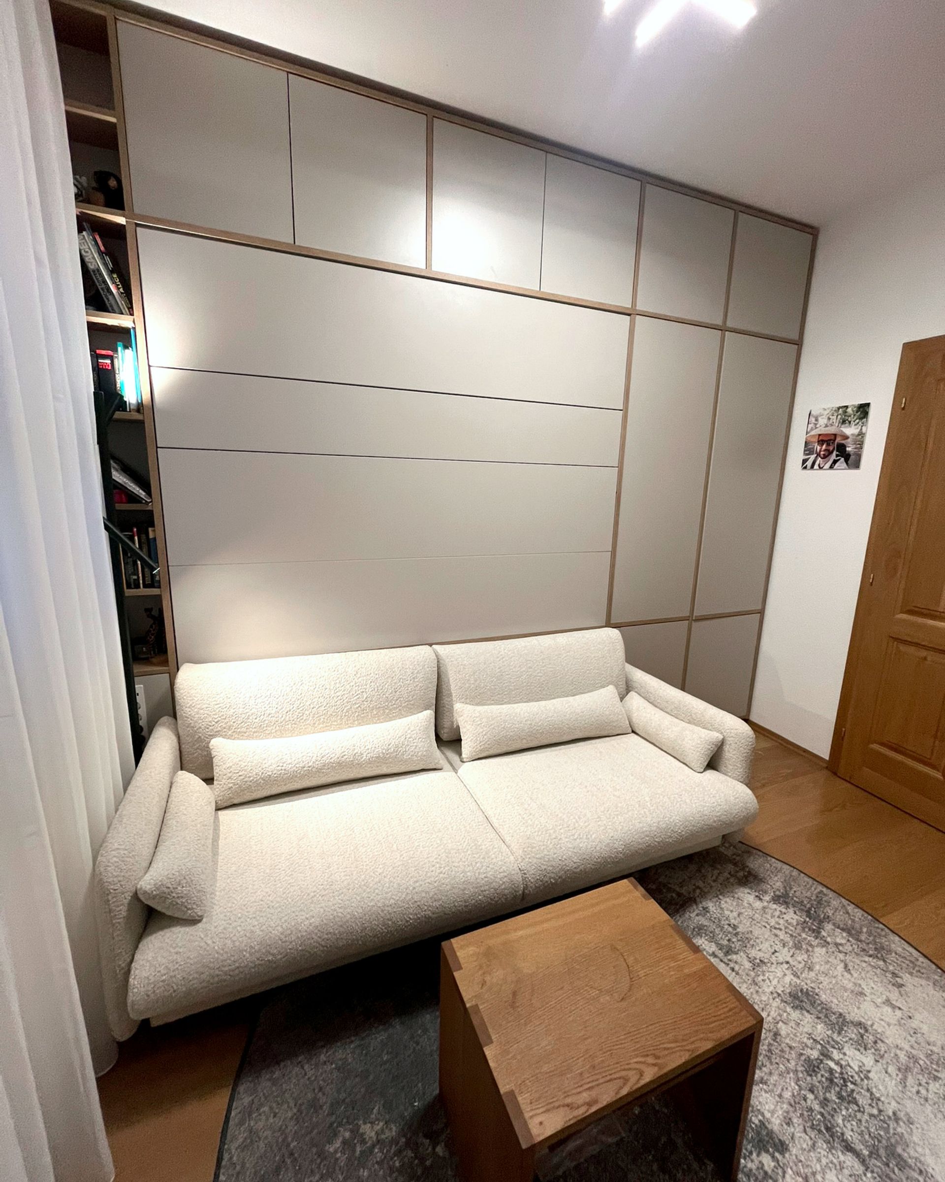 Beigefarbenes Sofa in einem Zimmer mit Holzvertäfelung und einem kleinen Holztisch auf einem Teppich.