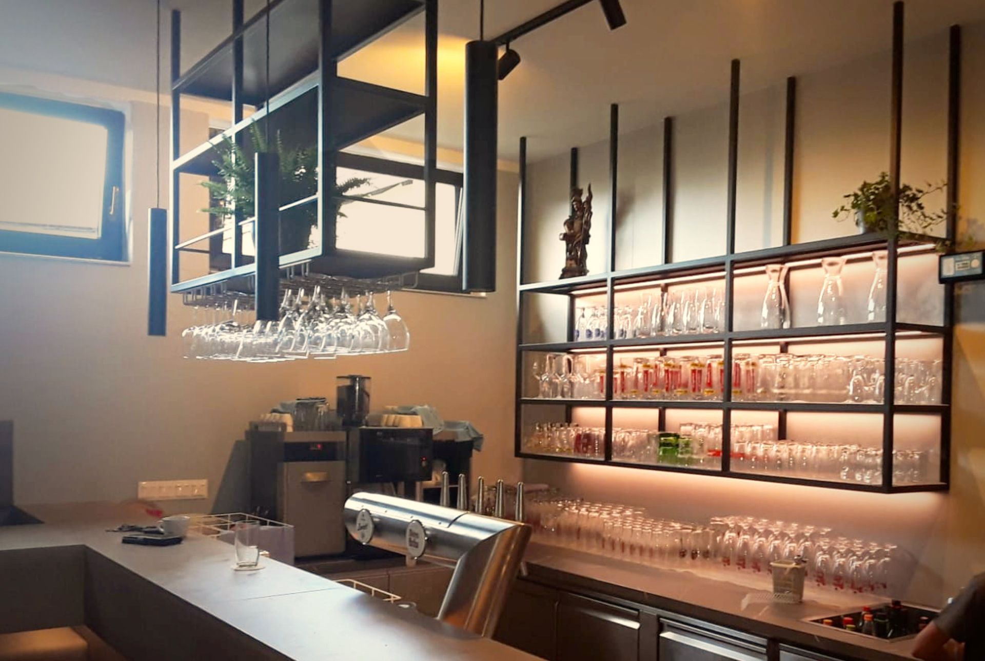Modern gestalteter Barbereich mit schwarzem Metallregal, Industrial Design und stimmungsvoller Beleuchtung im Gasthaus K