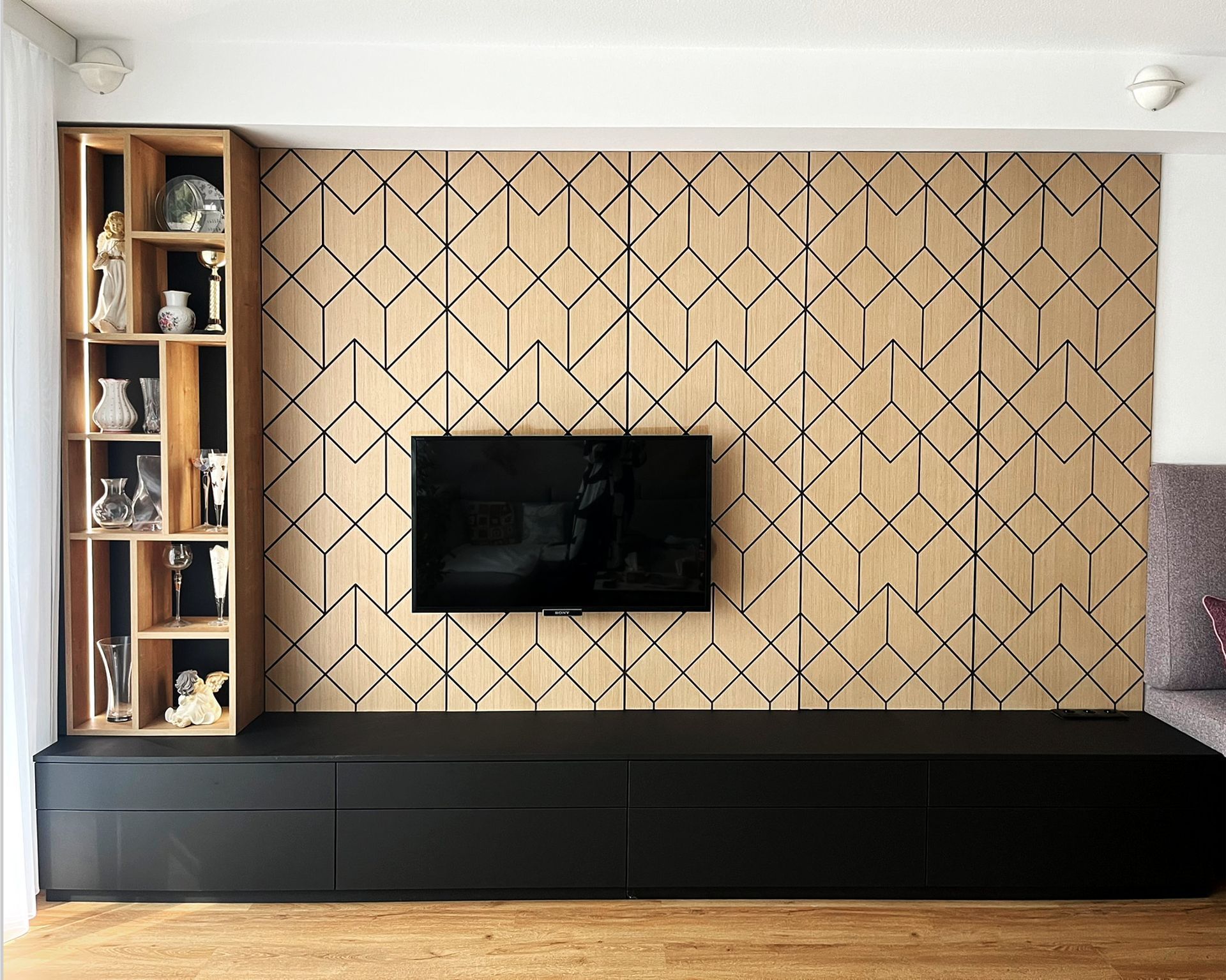 TV-Wand mit geometrischer Holzverkleidung, Stauraum und integriertem Fernseher nach dem Interior Redesign