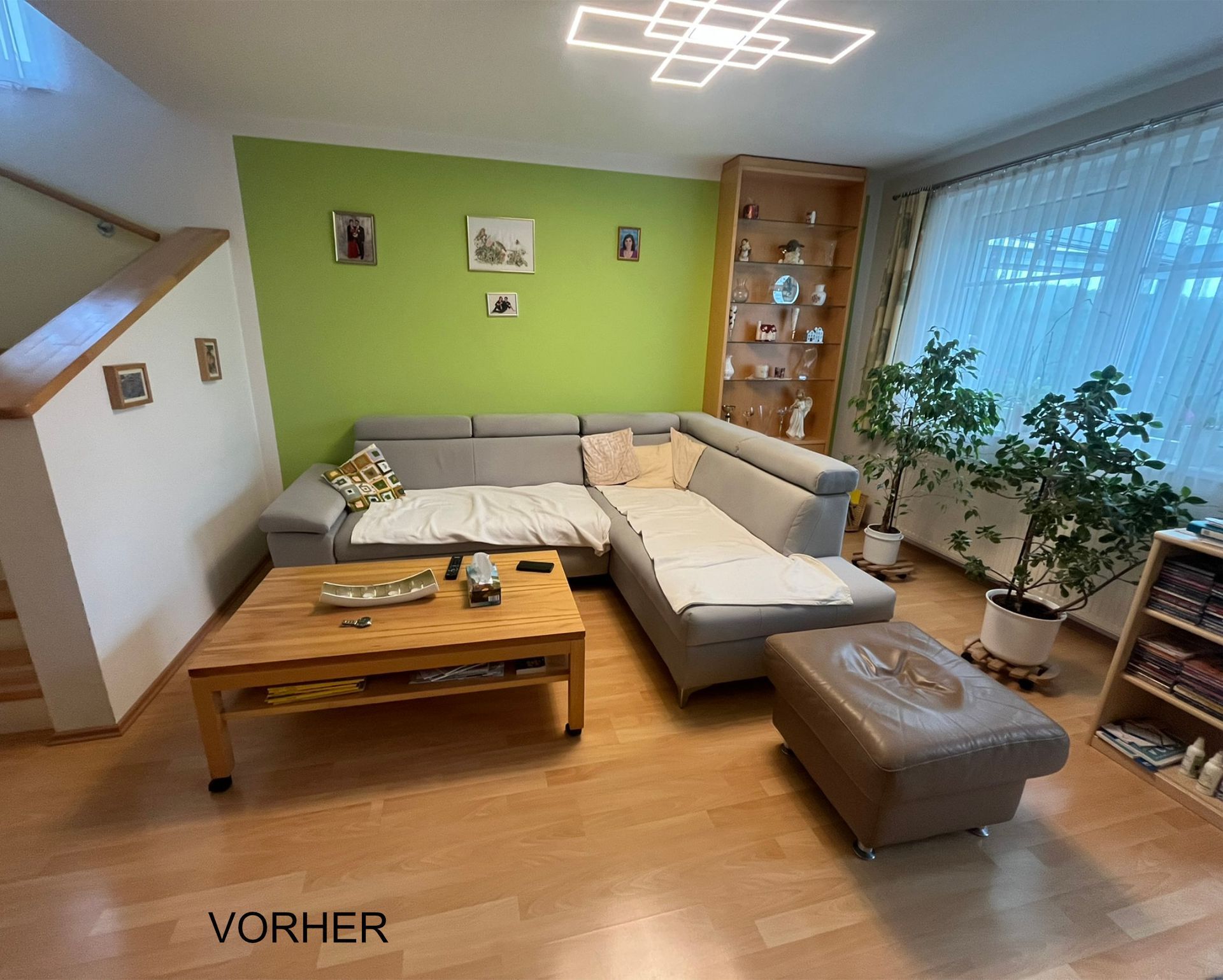 Vorher-Bild Wohnzimmer vor der Neugestaltung mit bestehender Einrichtung und grüner Wandfarbe