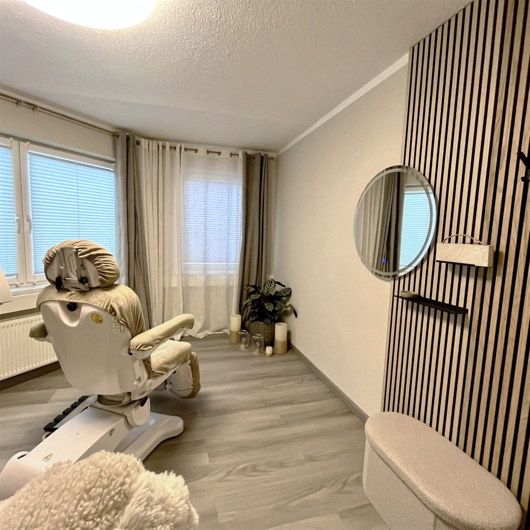 Beauty Lounge mit Akustikpaneel in Holzoptik, Vorhängen, rundem Spiegel und ruhiger Wohlfühlatmosphäre im Kosmetikinstitut