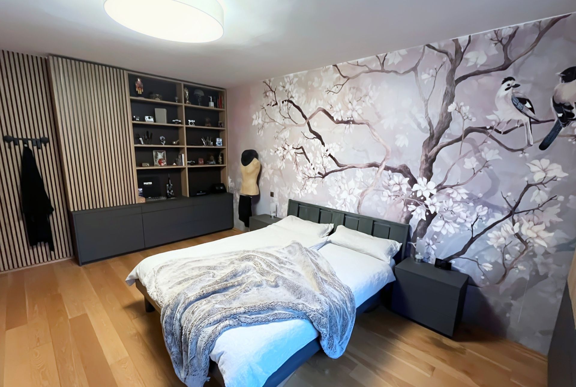 Modern gestaltetes Schlafzimmer mit anthrazitfarbenen Möbeln, Eiche-Lamellen und individueller Wandgestaltung