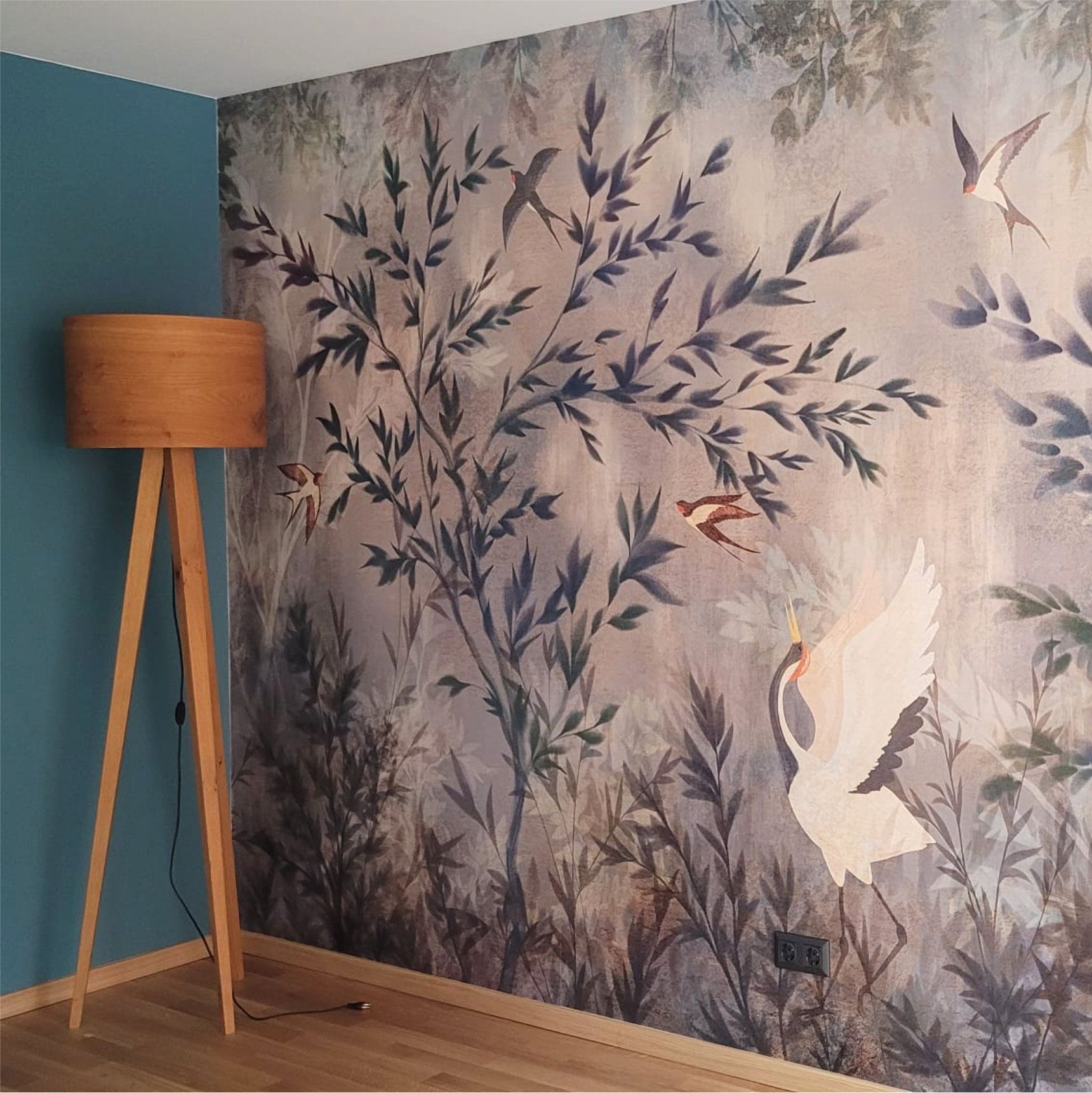 Behandlungsraum mit floraler Design-Tapete, petrolblauer Wandfarbe, Eichenboden und warmem Licht in moderner Physiotherapie-Praxis