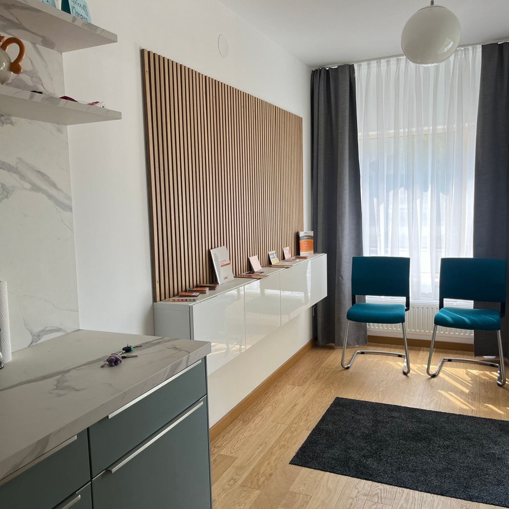 Wartezimmer mit blauen Stühlen, moderner Einrichtung und einer Akzentwand aus Holz.