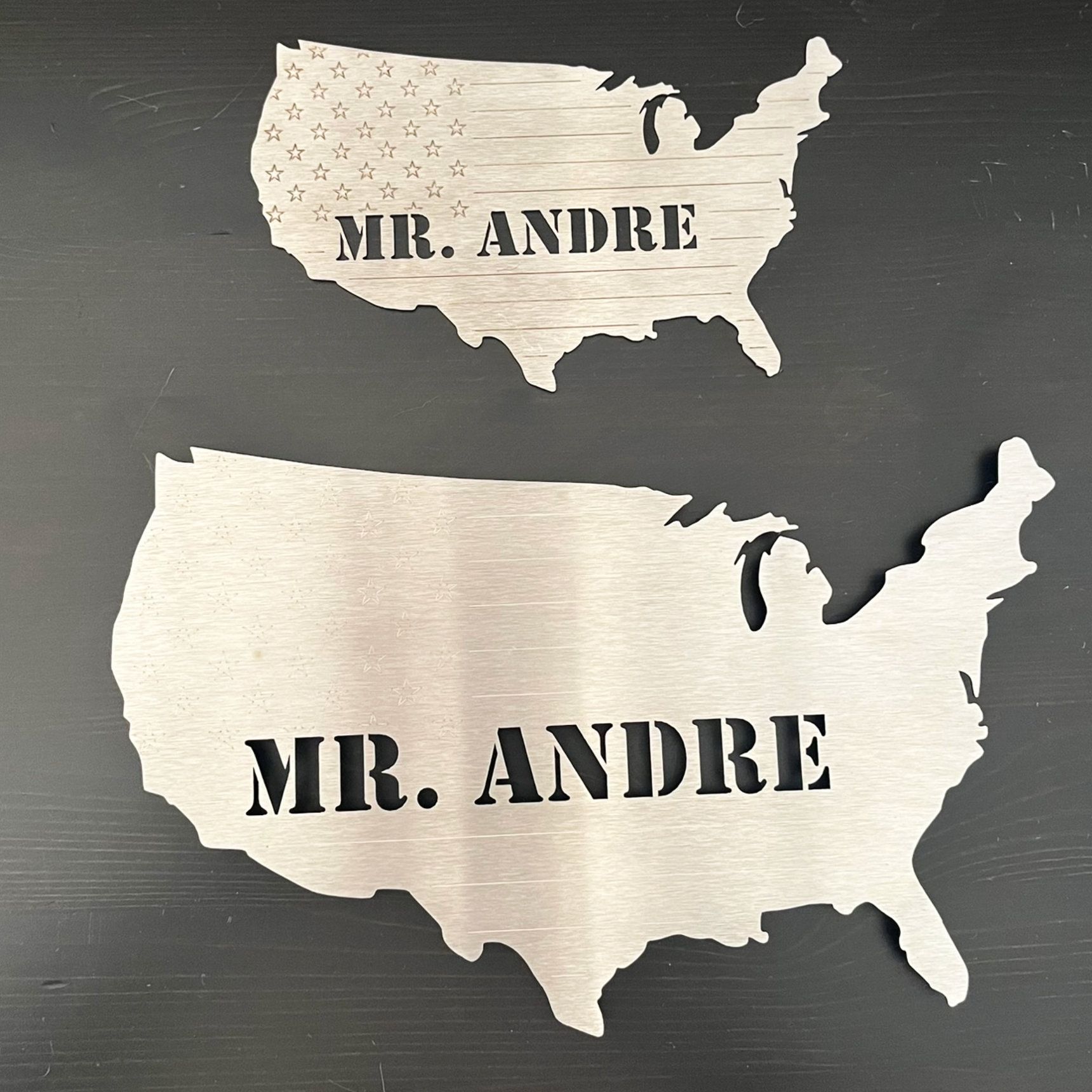 Zwei Metallfiguren der Vereinigten Staaten. Jede trägt die Aufschrift „MR. ANDRE“ in ausgeschnittenen Buchstaben.
