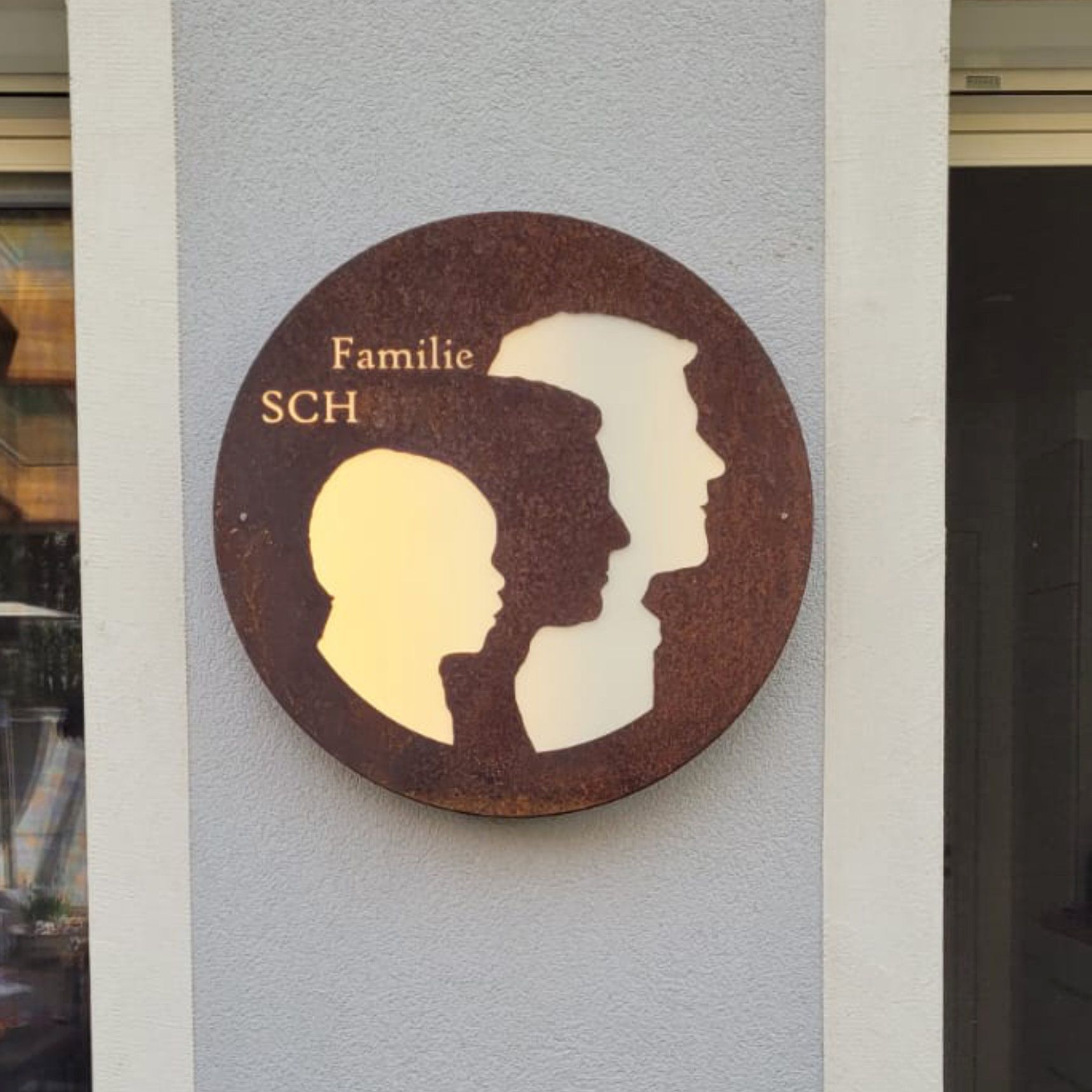 Rundes Familienschild mit Profilsilhouetten und dem Schriftzug