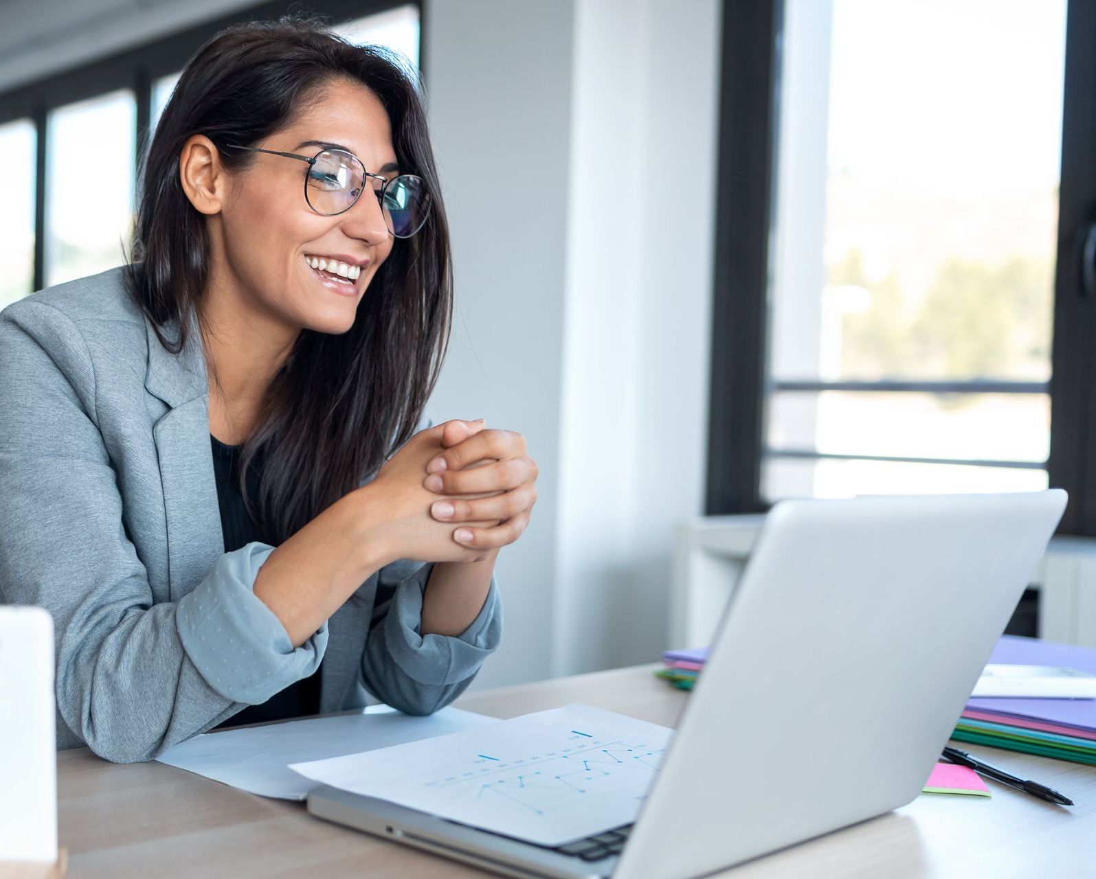 A woman smiling at a laptop screen