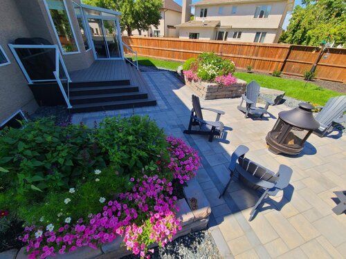A paver patio with chairs and a fire pit in the backyard