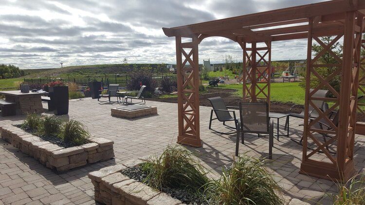 A patio with a pergola , chairs , tables and a fire pit.