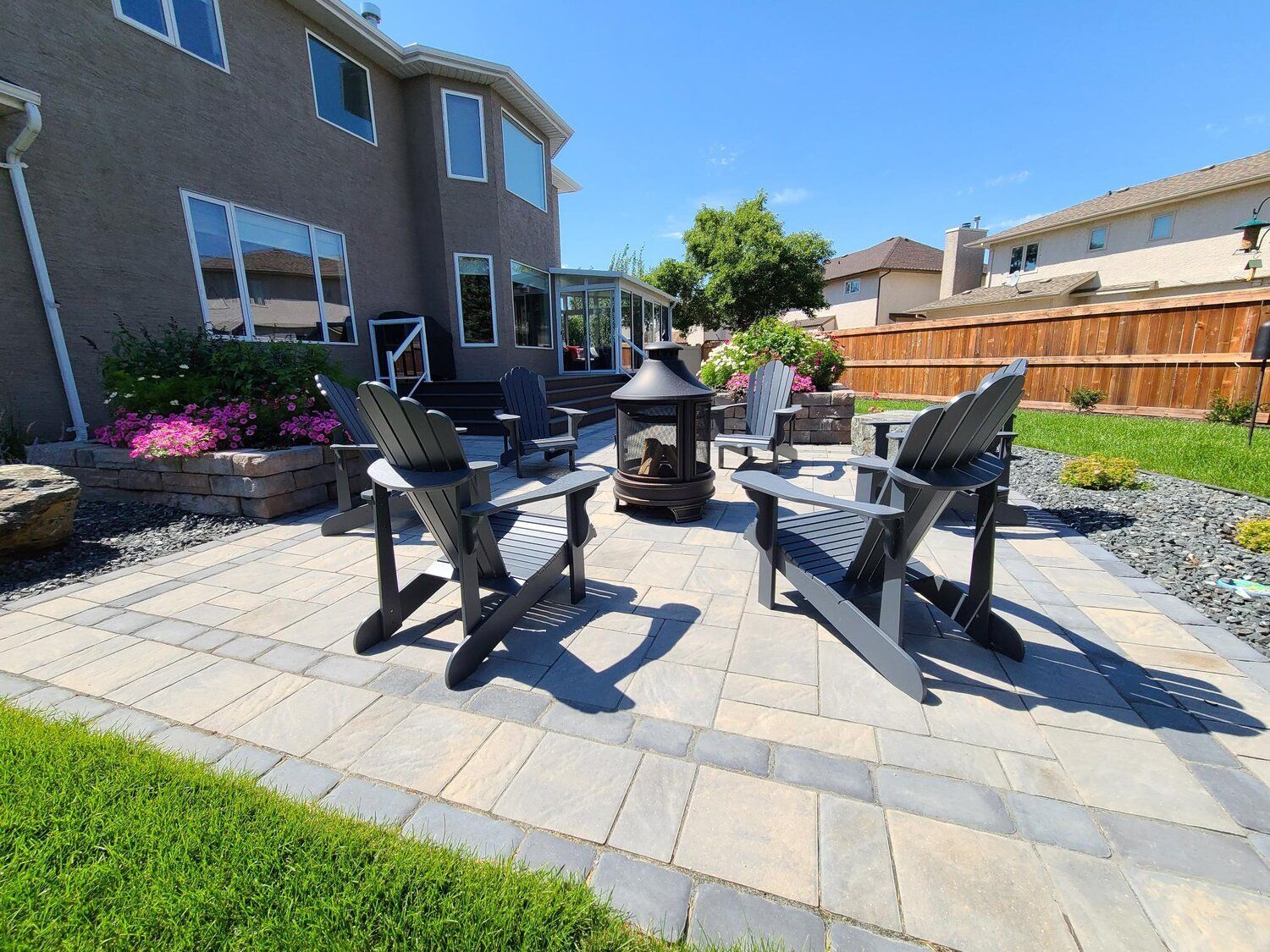 A patio with chairs and a fire pit in front of a house.