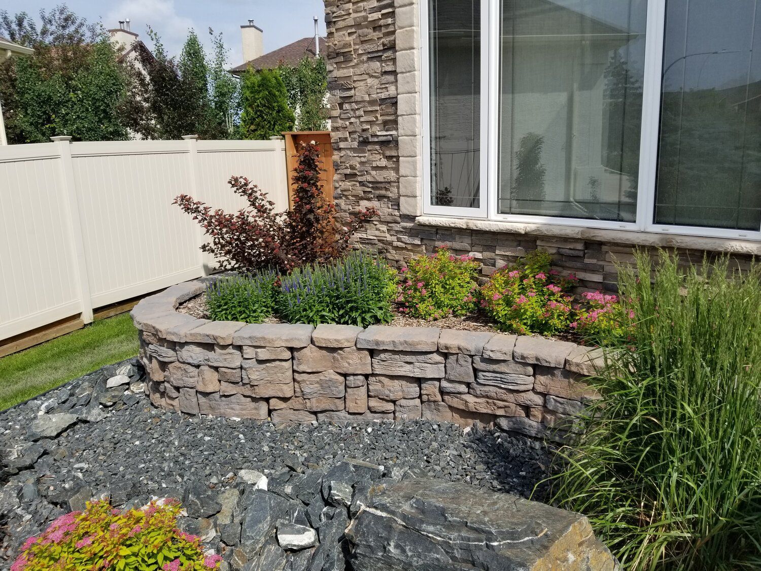 There is a stone wall in the garden in front of the house.