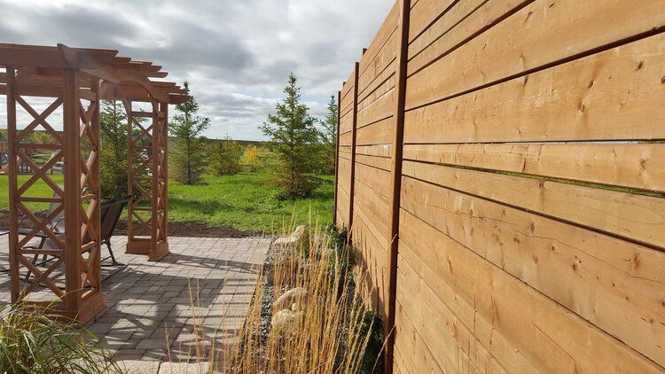 A wooden fence with a pergola in the background.