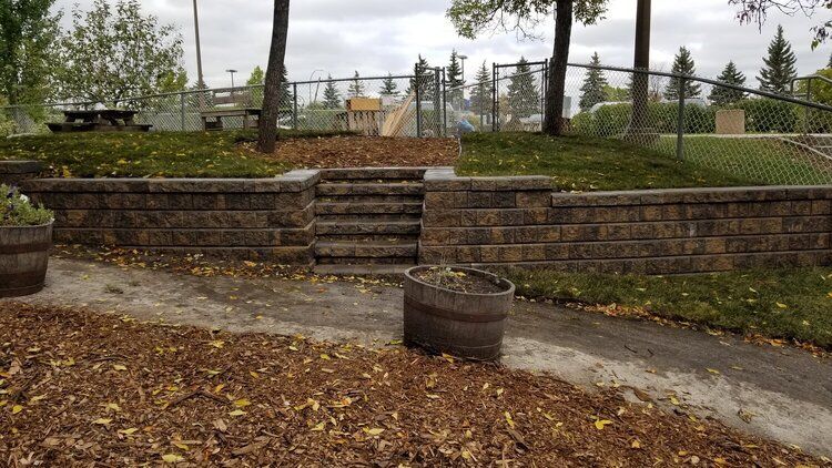 A stone wall with stairs leading up to a picnic area.