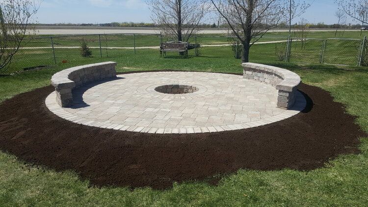 A circular patio with a fire pit in the middle of it.