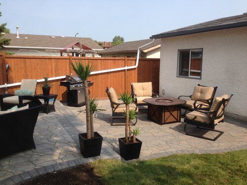 A patio with furniture and a fire pit in front of a house.