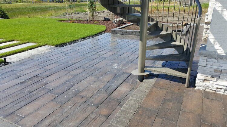 A paved patio deck with a spiral staircase in the background.