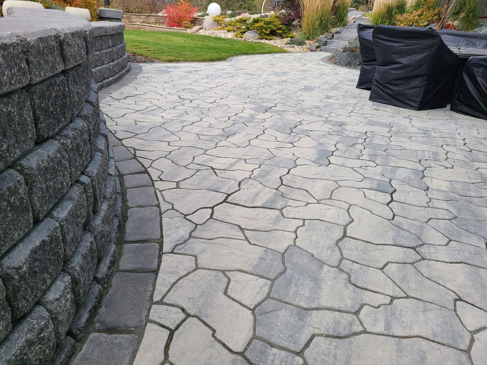 A stone walkway leading to a patio with a black chair cover.