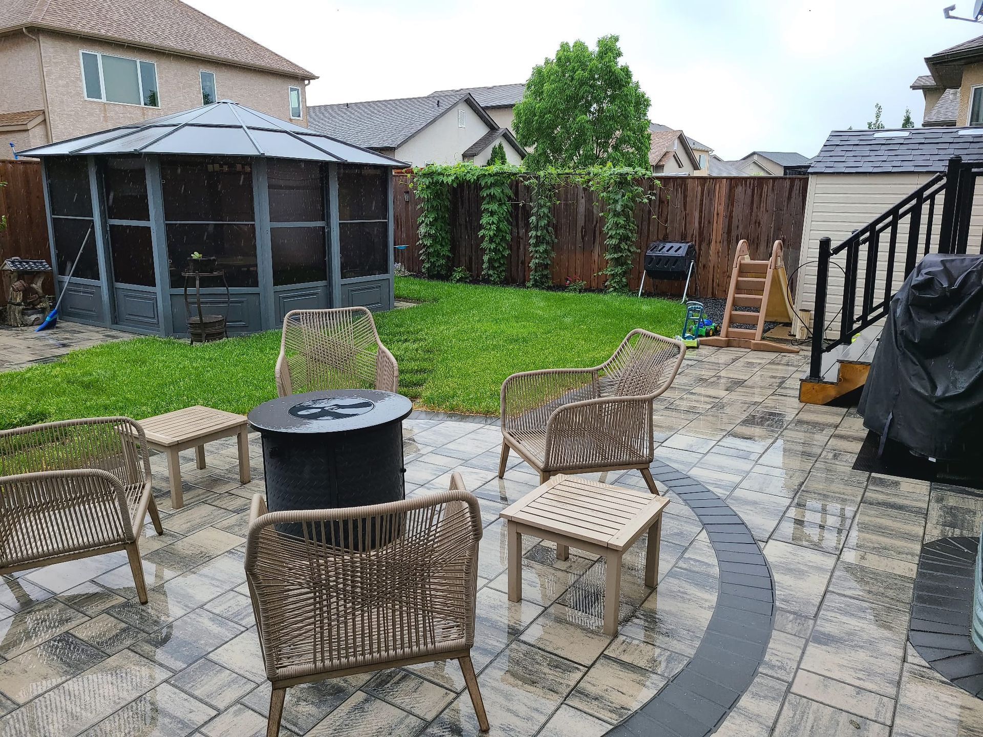 A patio with chairs , tables and a gazebo in the backyard.