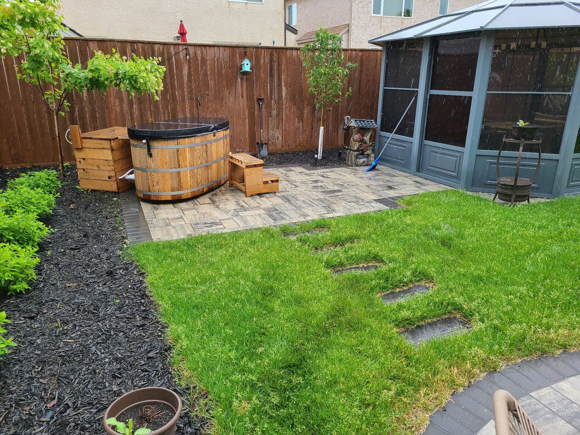 A backyard with a gazebo , wooden barrels , and a hot tub.