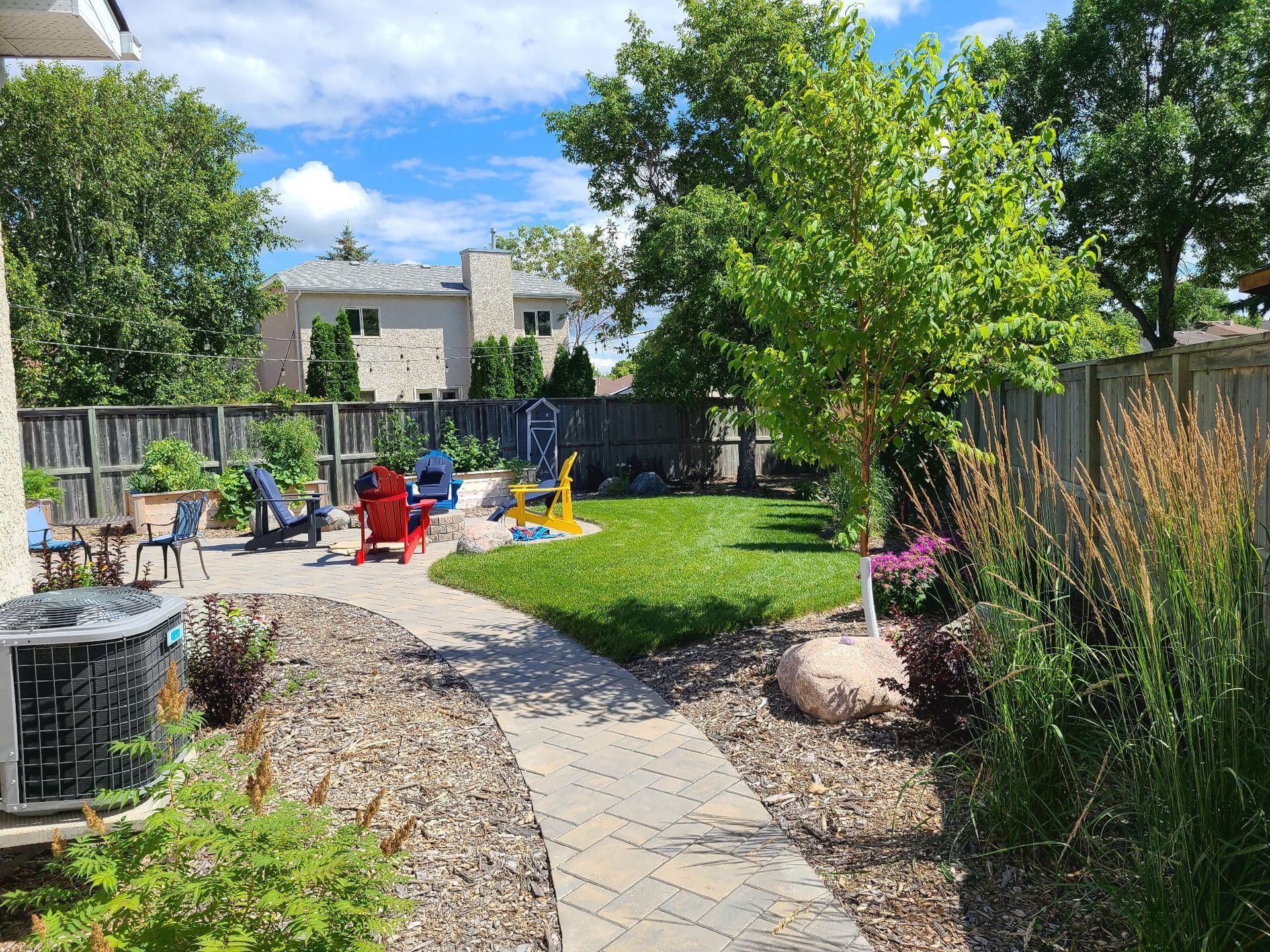 A backyard with a walkway leading to a patio