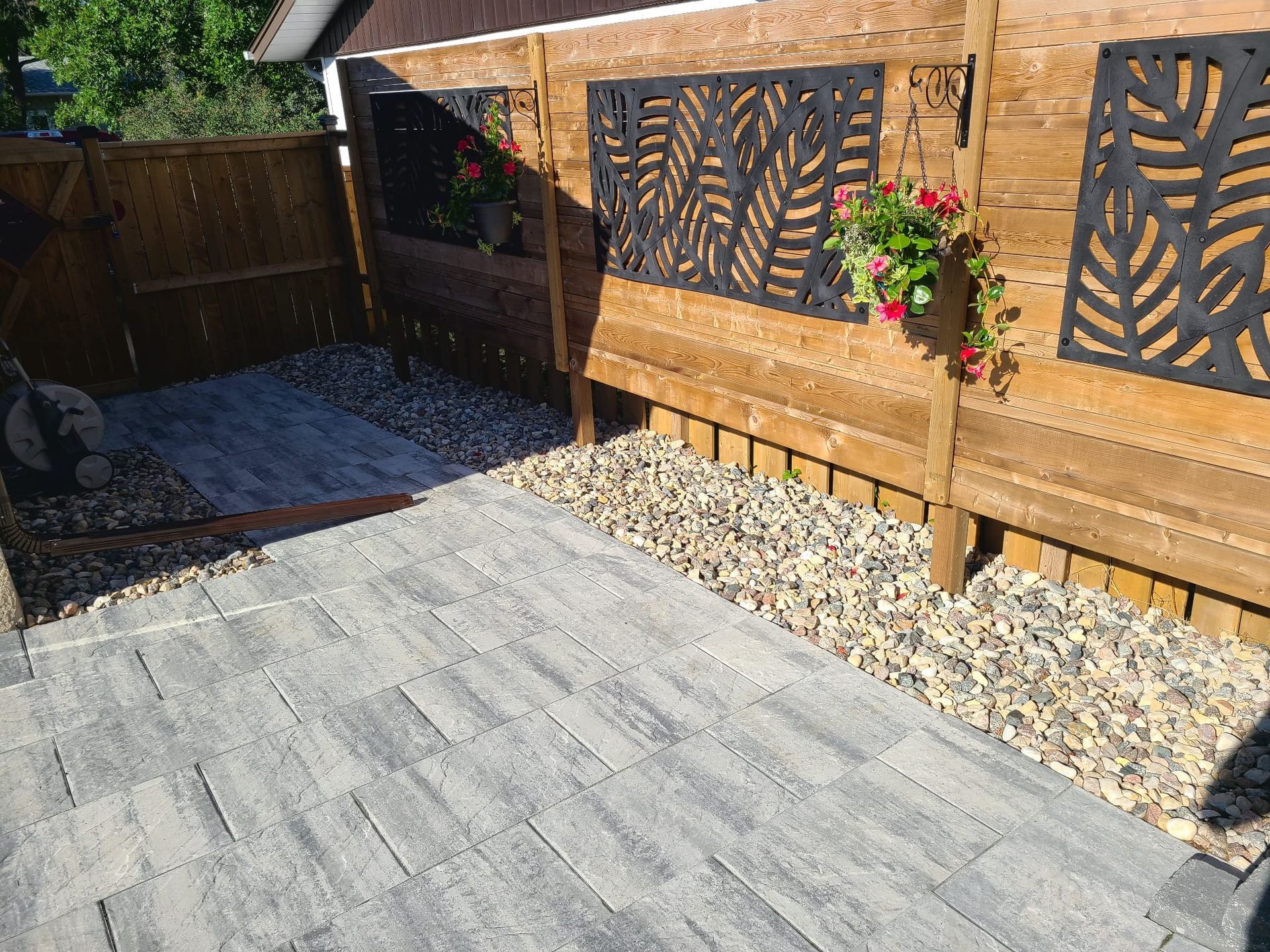 A patio with a wooden fence and a planter with flowers on it.