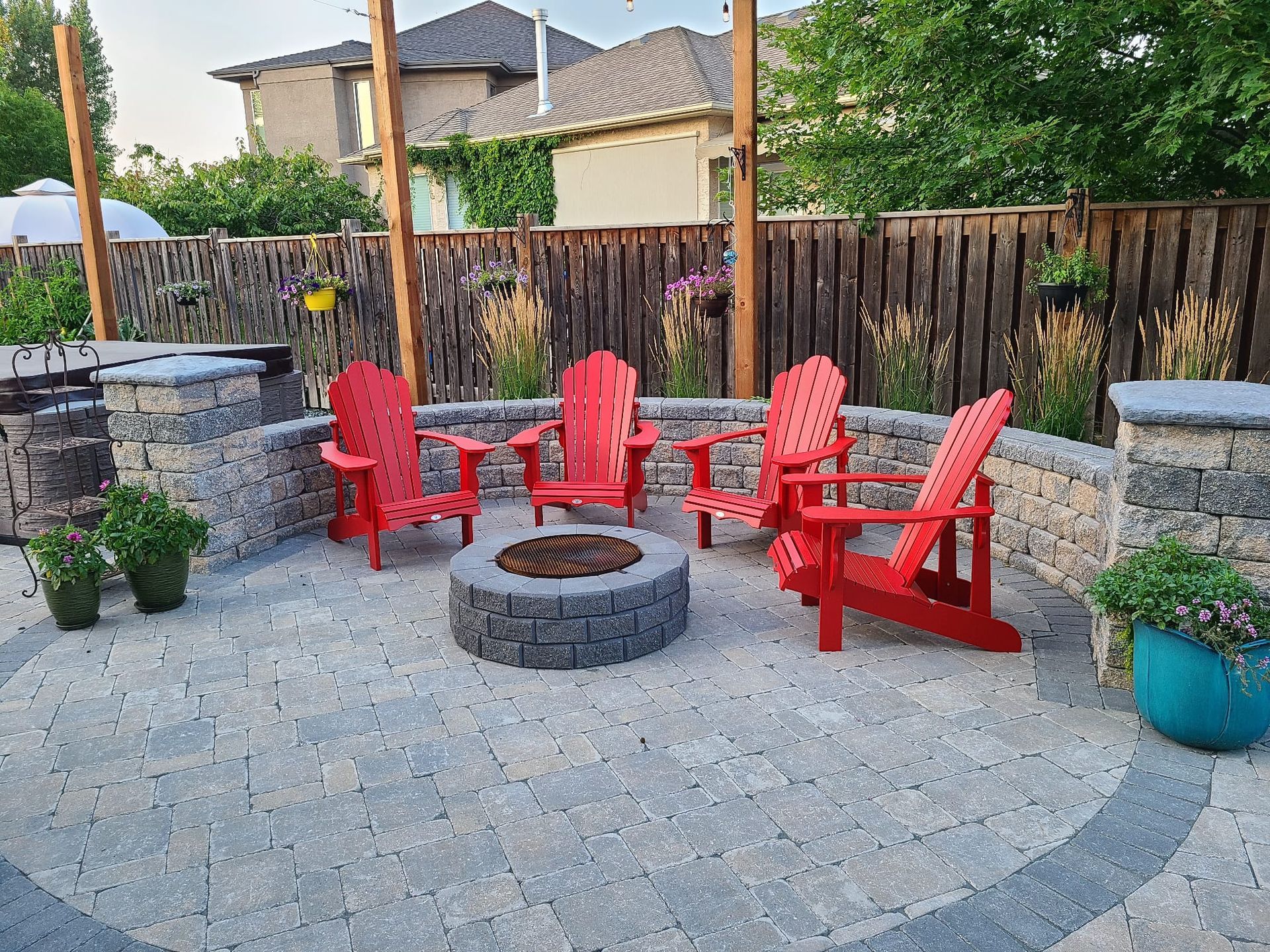 A fire pit surrounded by red chairs on a patio.