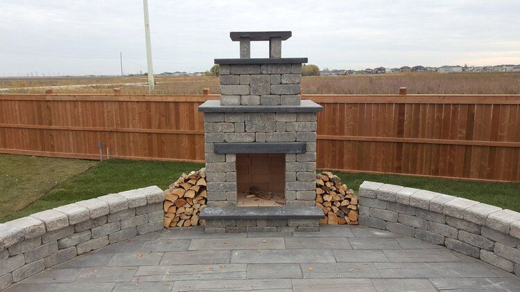 An outdoor brick fireplace with a wooden fence in the background