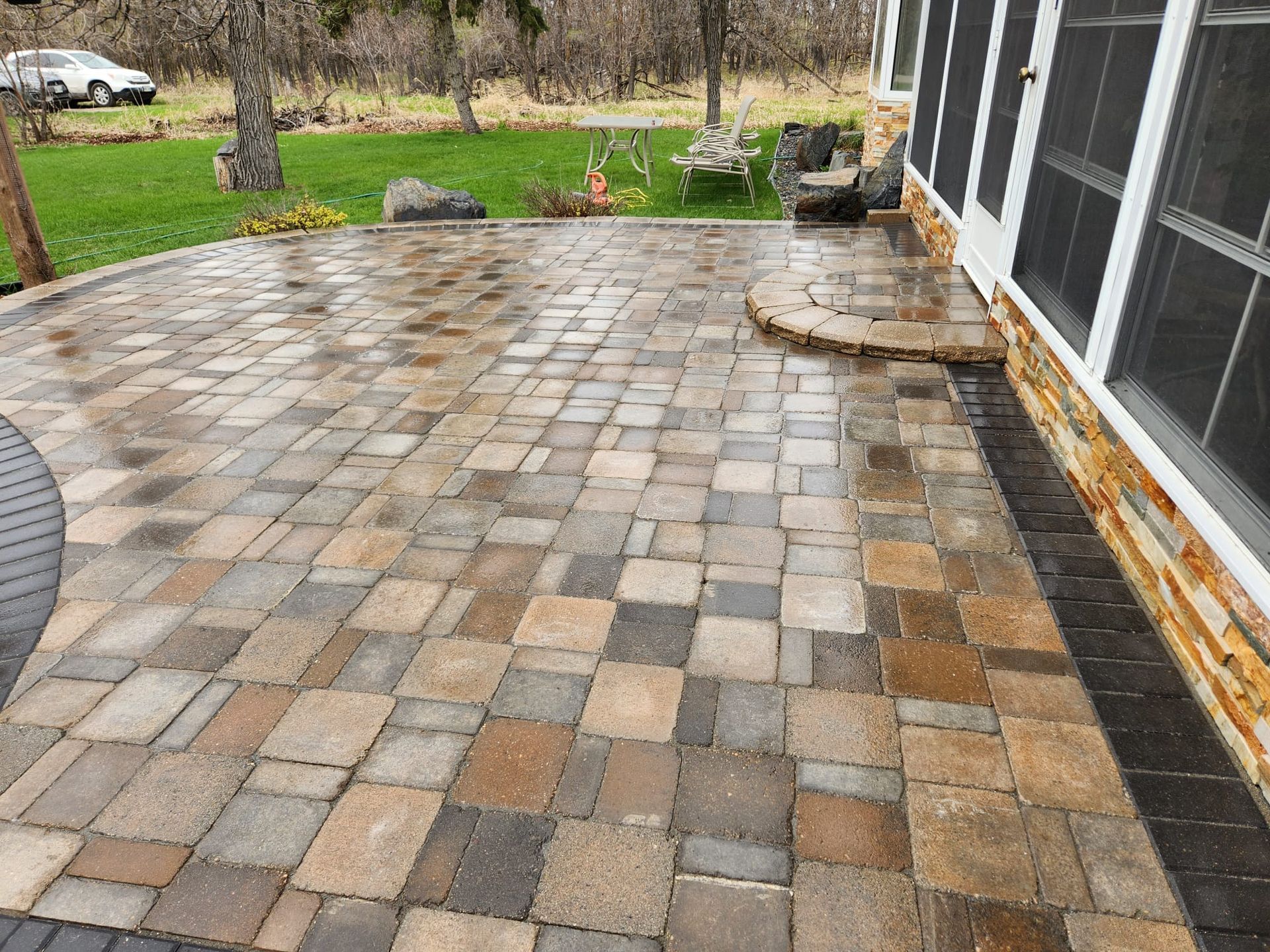 A paver patio with a table and chairs in front of a house.