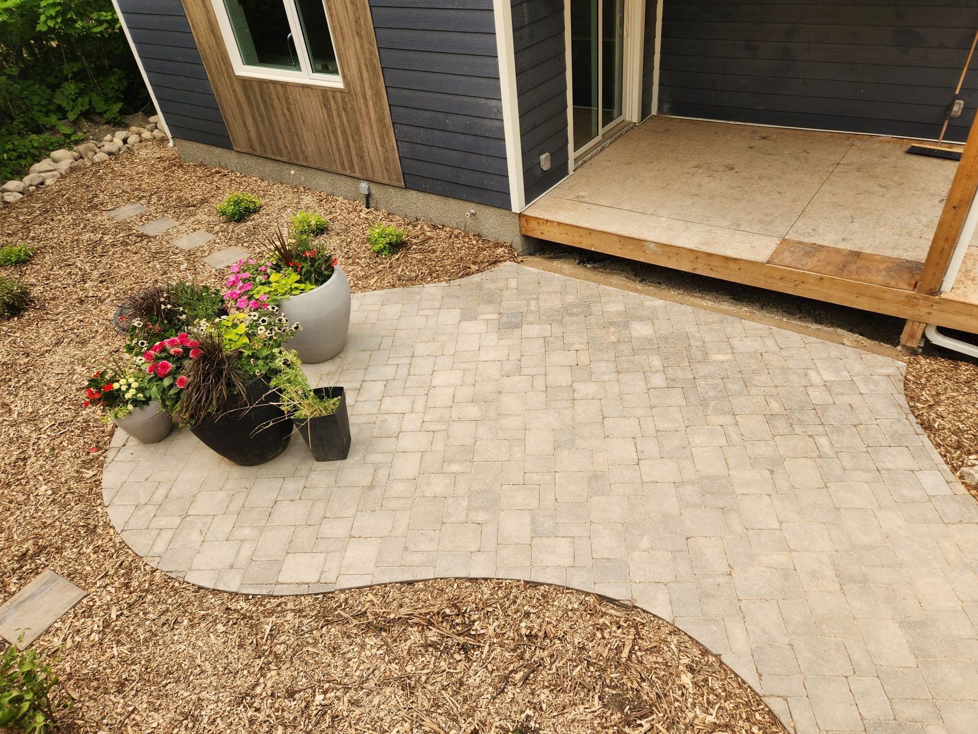 A patio with flowers and potted plants in front of a house.