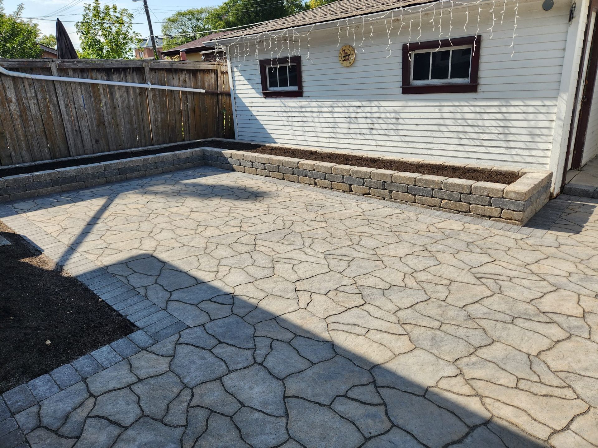 A backyard with a patio and a fence in front of a house.