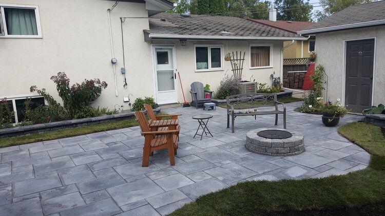 A paver patio with a fire pit and chairs