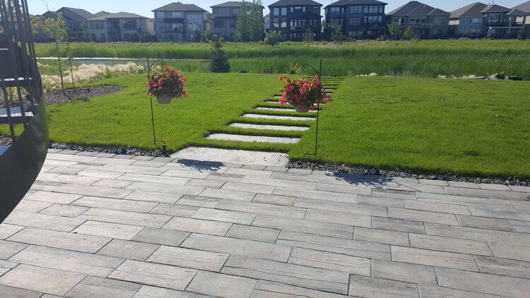 A patio with steps leading to a grassy field with houses in the background.