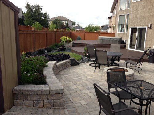 A patio with a table and chairs and a fire pit.