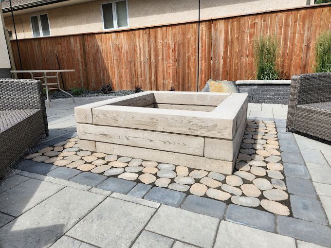 A fire pit is sitting on top of a patio next to a wooden fence.