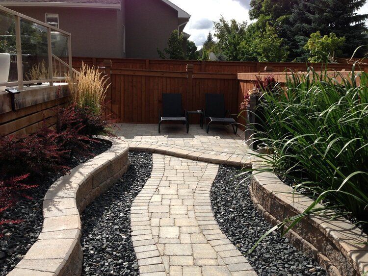 A brick walkway leading to a patio with chairs