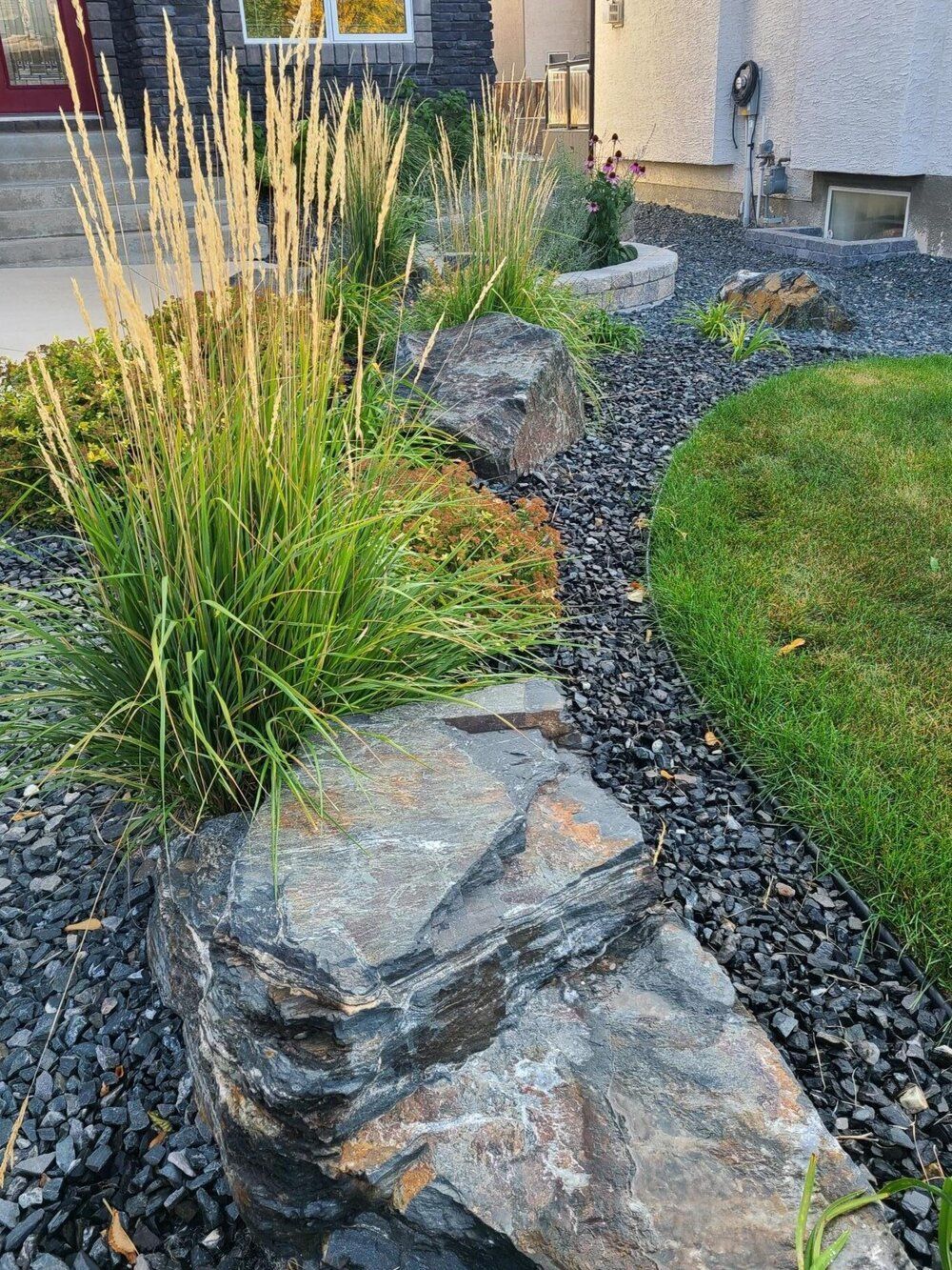 A garden with rocks and plants in front of a house.