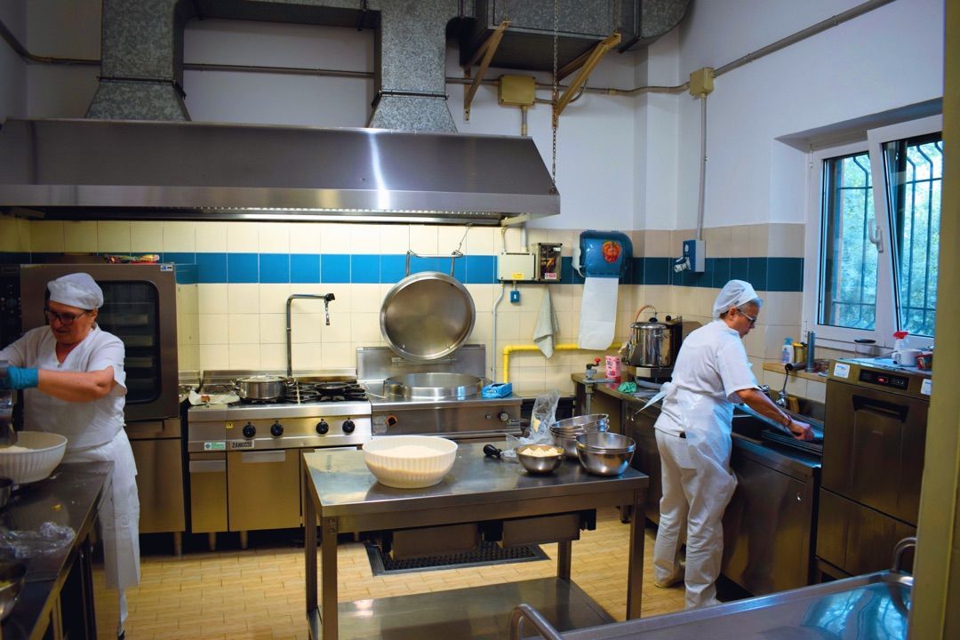 Cucina professionale con due chef al lavoro vicino a banconi e fornelli in acciaio inox.